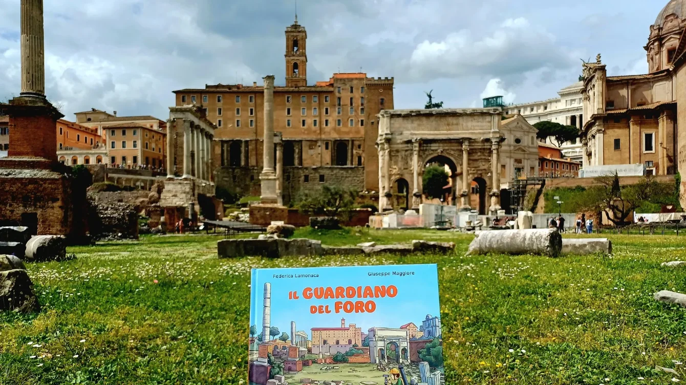 Copertina del silent book "Il Guardiano del Foro" sul prato, con le rovine del Foro Romano e l'Arco di Settimio Severo a Roma.